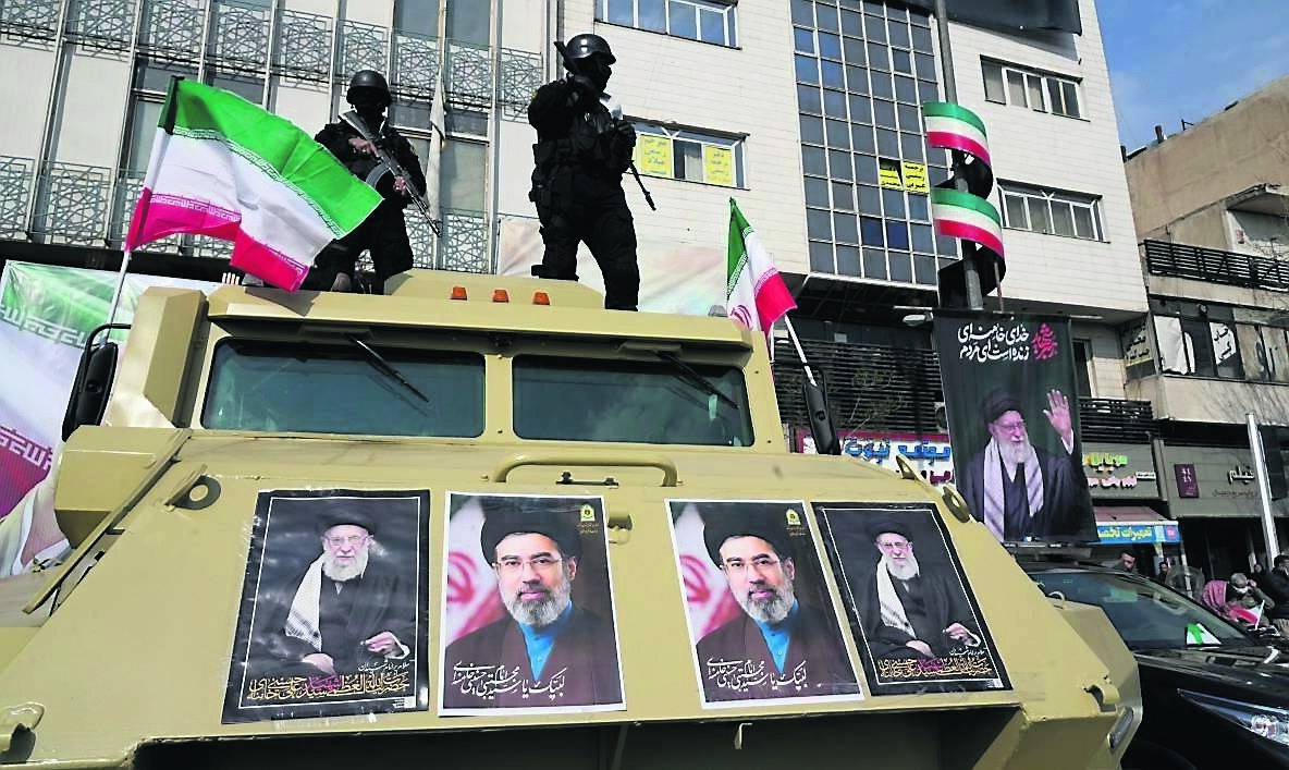 Policemen stand on top of their car with pictures of the late Iranian supreme leader Ayatollah Ali Khamenei and his son and successor Ayatollah Mojtaba Khamenei during a rally of support in Tehran, Iran.  	Picture: Vahid Salemi/AP
            