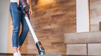 oman cleaning floor and carpet with cordless vacuum cleaner at home.