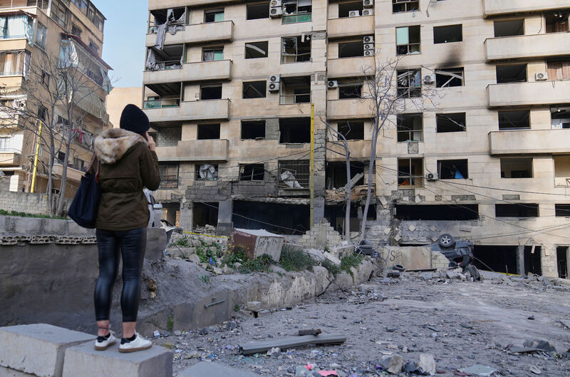 A woman speaks on the phone, as she checks a damaged building that was hit by Israeli airstrikes in central Beirut. Picture: AP Photo/Hussein Malla