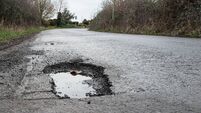 Deep road pothole filled with rainwater.