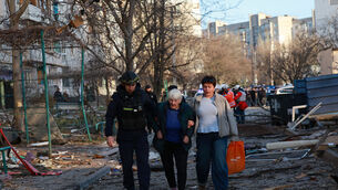 A rescuer helps an elderly woman to leave her home damaged by Russian aerial guided bomb in Zaporizhzhia, Ukraine (Kateryna Klochko/AP)