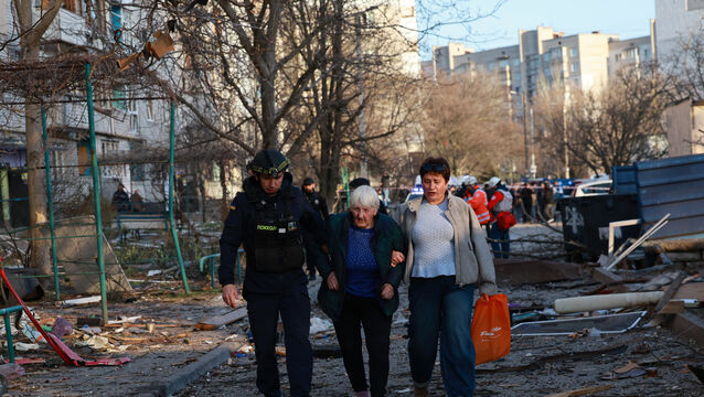 A rescuer helps an elderly woman to leave her home damaged by Russian aerial guided bomb in Zaporizhzhia, Ukraine (Kateryna Klochko/AP)