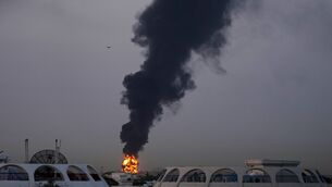 <p>Fire and plumes of smoke rise after a drone struck a fuel tank forcing the temporary suspension of flights. near Dubai International Airport. Picture: AP</p>