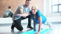 Senior woman exercising with trainer at rehab