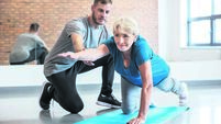 Senior woman exercising with trainer at rehab