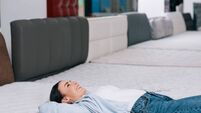 side view of smiling customer lying on orthopedic mattress in furniture store