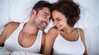 High angle view of smiling couple relaxing on bed