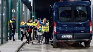 <p>A mother with her five-month-old baby and six-year-old son, carrying a blue teddy, is escorted onto a Garda vehicle for deportation under Operation Trench last November. Picture: Chani Anderson</p>