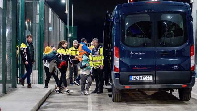 <p>A mother with her five-month-old baby and six-year-old son, carrying a blue teddy, is escorted onto a Garda vehicle for deportation under Operation Trench last November. Picture: Chani Anderson</p>