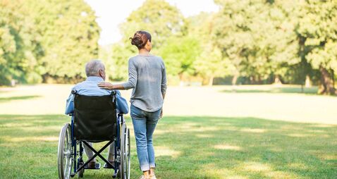 Senior man sitting on a wheelchair with caregiver