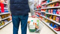 Man holding shopping basket with bread and milk groceries in supermarket