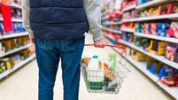 Man holding shopping basket with bread and milk groceries in supermarket