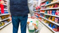 Man holding shopping basket with bread and milk groceries in supermarket