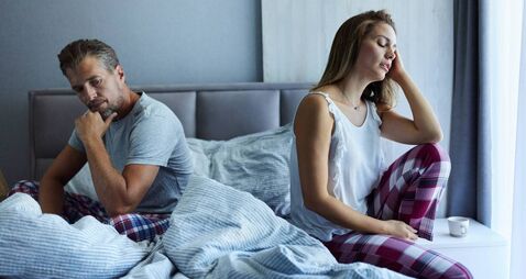 Displeased couple having problems in a bedroom.