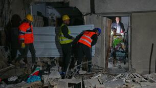Residents carry personal belongings as they leave a building damaged in a missile strike in Tel Aviv (Maya Levin/AP)
