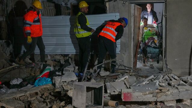 <p>Residents carry personal belongings as they leave a building damaged in a missile strike in Tel Aviv (Maya Levin/AP)</p>