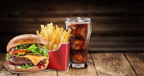Delicious cheeseburger with cola and potato fries on the wooden table. Fast food concept.
