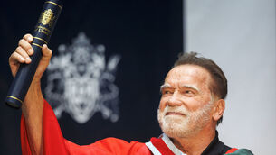 <p>Arnold Schwarzenegger lifts his honorary doctorate presented to him by the Ulster University in Belfast. Picture: Liam McBurney/PA</p>