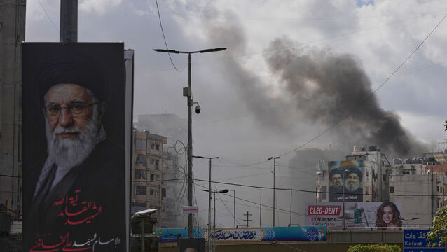 A portrait of Iran’s late supreme leader Ayatollah Ali Khamenei, left, is seen as smoke rises following an Israeli airstrike in Dahiyeh, Beirut’s southern suburbs, Lebanon (Hassan Ammar/AP)