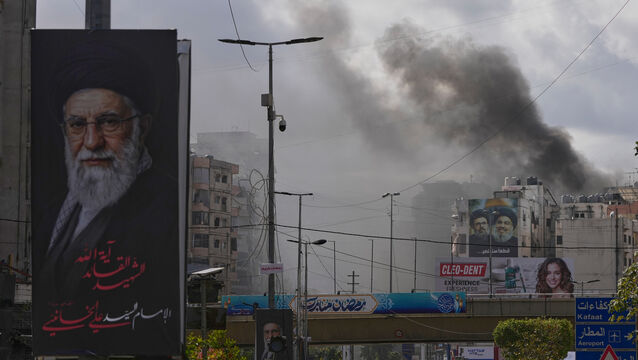 <p>A portrait of Iran’s late supreme leader Ayatollah Ali Khamenei, left, is seen as smoke rises following an Israeli airstrike in Dahiyeh, Beirut’s southern suburbs, Lebanon (Hassan Ammar/AP)</p>