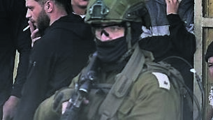 <p>An Israeli soldiers aims a weapon during a military operation at a market in the Balata refugee camp in the West Bank, as Palestinians stand nearby. Picture: Majdi Muhammad</p>