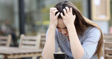 Sad woman complaining alone sitting on a coffee shop terrace
