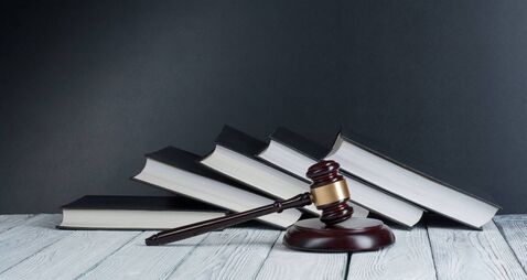 Law concept - Open law book with a wooden judges gavel on table in a courtroom or law enforcement office isolated on white backg