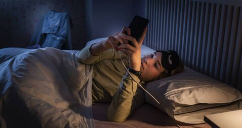 Teenage girl suffering sleeping disorders using smartphone at night