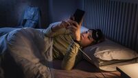 Teenage girl suffering sleeping disorders using smartphone at night