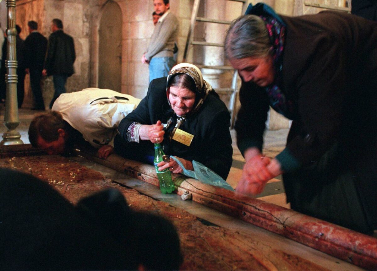 A Christian pilgrim collects holy water from the Stone of Unction where tradition says Jesus’ body was laid out and washed after he died, at the Church of the Holy Sepulchre in Jerusalem, in 1999. File picture: Ruth Fremson/AP A Christian pilgrim collects holy water from the Stone of Unction where tradition says Jesus’ body was laid out and washed after he died, at the Church of the Holy Sepulchre in Jerusalem, in 1999. File picture: Ruth Fremson/AP