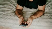 Person using smartphone while relaxing on a comfortable striped bed