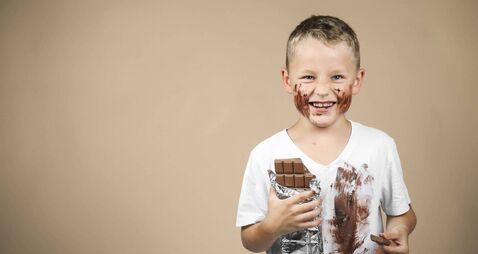 Little boy holds a bar of chocolate in his hand