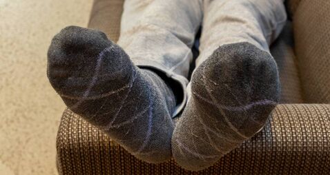 Man lying on sofa with feet up on armrest