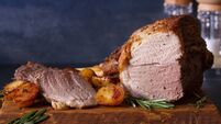 Roast leg of lamb with potatoes and rosemary on serving wooden board