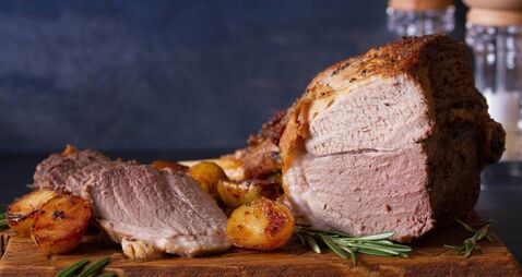 Roast leg of lamb with potatoes and rosemary on serving wooden board