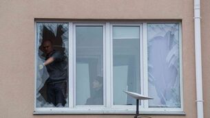People remove broken glass from their windows after a Russian strike on a residential neighbourhood in Kriukivshchyna, Kyiv region, Ukraine (Evgeniy Maloletka/AP)
