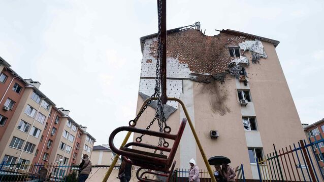 People walk in front of a house which was damaged after a Russian strike on residential neighbourhood in Kriukivshchyna, in the Kyiv region (Evgeniy Maloletka/AP)