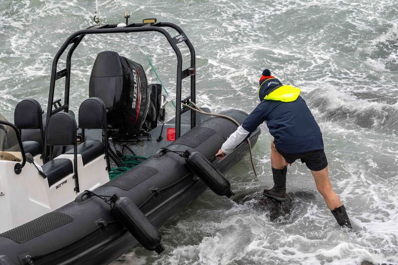 Strong winds caused a RIB to break its moorings and smash onto the rocks in Schull. The boat owners were seen attempting to save the boat. Picture: Andy Gibson