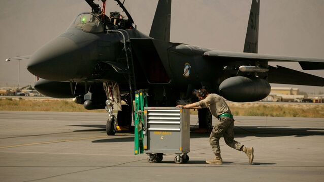 <p>A US Air Force airman pushes a cart past an F-15E Strike Eagle at Bagram Air Field in Afghanistan (Maya Alleruzzo/AP)</p>