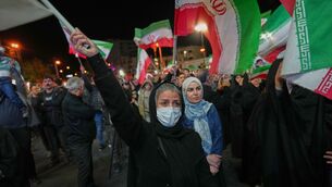 Women hold Iranian flags during a pro-government gathering in a square in Tehran (Francisco Seco/AP)