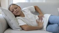 Girl Lying on Sofa with Stomach Ache at Home