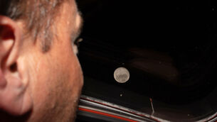 <p>Artemis II commander and NASA astronaut Reid Wiseman looks out one of the Orion spacecraft's main cabin windows at the Moon ahead of the crew's lunar flyby on April 6, 2026. (NASA via AP)</p>