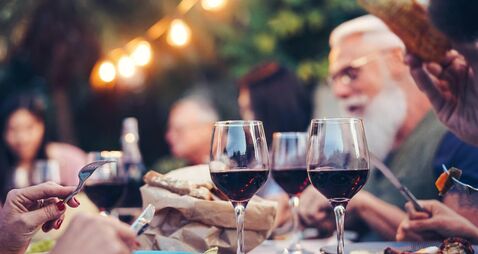 Happy family eating and drinking red wine at dinner barbecue party outdoor - Mature and young people dining together on rooftop