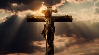 Dramatic crucifixion scene with sun rays and clouds