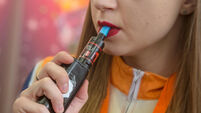 A young woman smokes electronic cigarettes