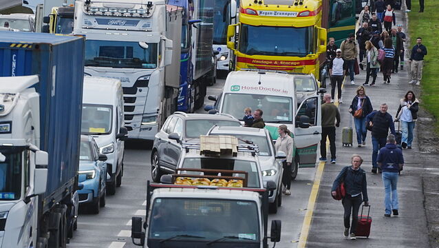 <p>People with their luggage walk past the heavy traffic on Dublin's M50 Northbound, due to vehicles taking part on the third day of a national fuel protest against rising fuel prices. Picture: Philip Toscano/PA</p>
