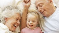 Grandparents Cuddling Granddaughter In Bed