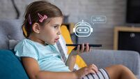 Little girl talking to friendly chatbot character on phone at home