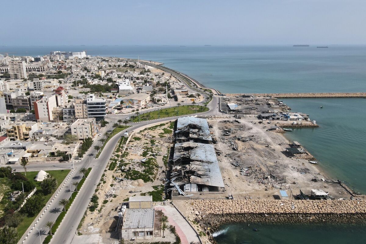 Backdropped by ships in the Strait of Hormuz, damage, according to local witnesses caused by several recent airstrikes during the U.S.-Israel military campaign, is seen on a fishing pier in the port of Qeshm island, Iran, Monday, April 13, 2026. (AP Photo/Asghar Besharati)