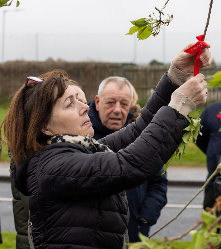 Family member Maria Doyle ties a ribbon to a tree planted in memory of Grace.